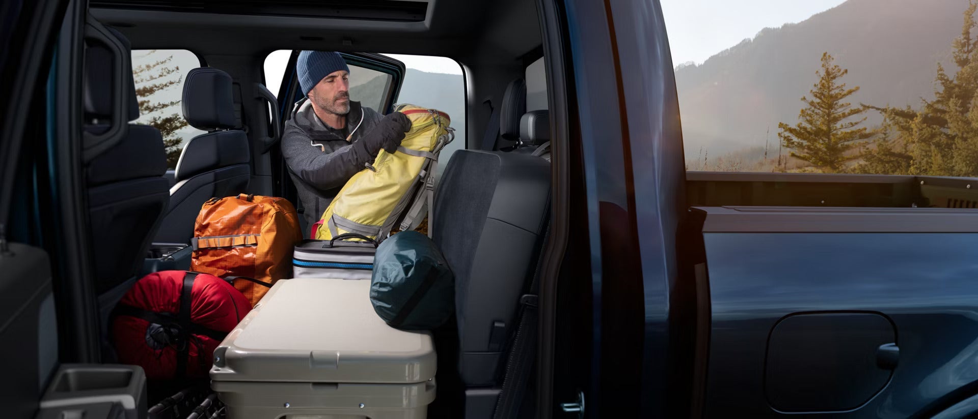 2026 Ford F-150 interior view of a man packing the back seat with camping gear